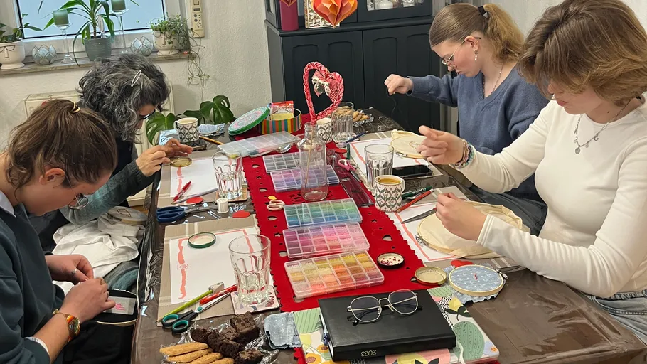 Four women engaged in handicrafts at a table.