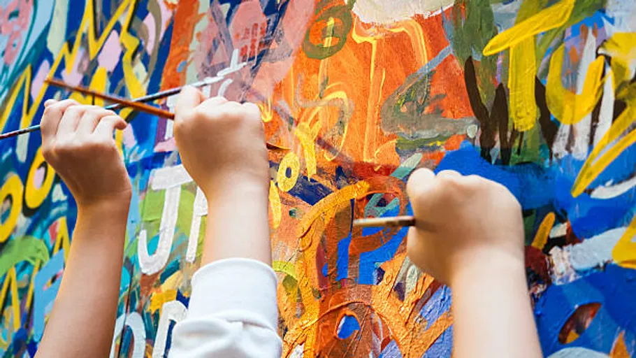 Children painting a colorful wall mural.
