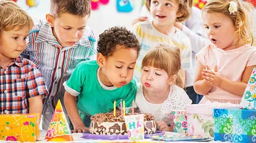 Children blowing birthday candles at party.