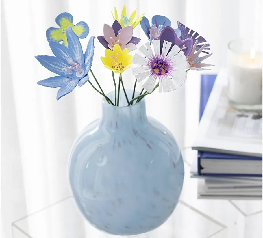 Paper flowers in blue vase on table.