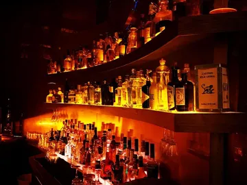 Shelved spirits are illuminated on wooden shelves in the bar.