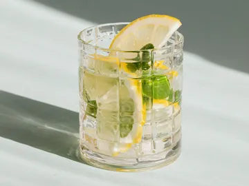 Glass with lemon slices and mint on a bright table.