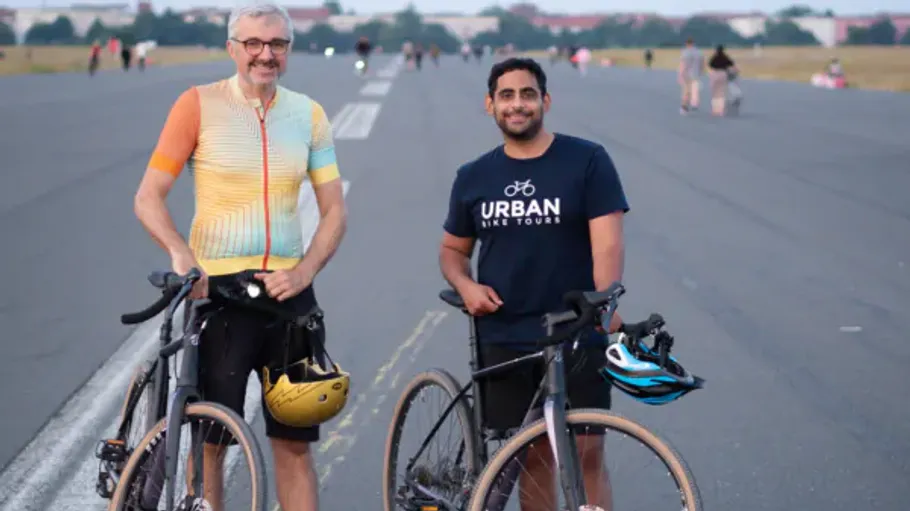 Two men with bikes on an open roadway.
