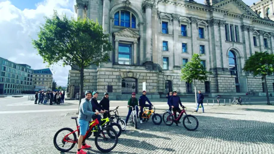 Group of cyclists in front of historic building.