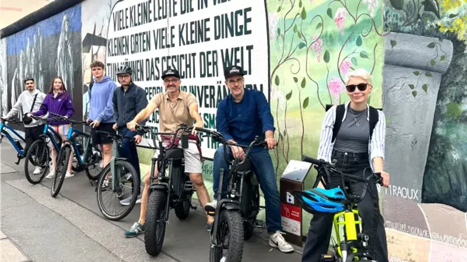 Group of cyclists in front of graffiti mural.