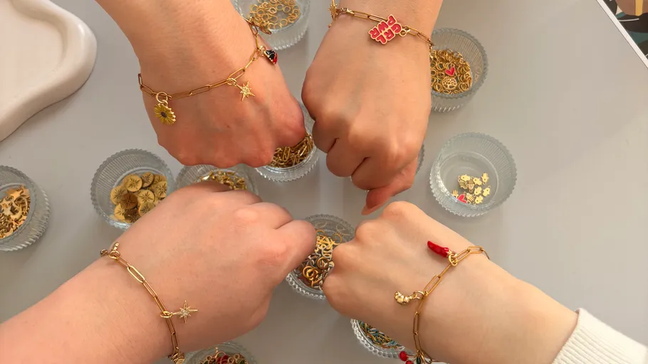 Vier Hände mit Charm-Armbändern über Schüsseln.