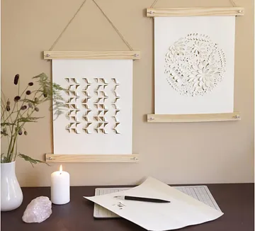 Papierkunst an der Wand und Werkzeuge auf Tisch.