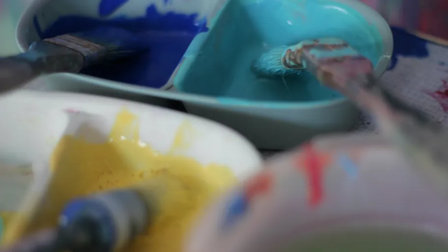 Paintbrushes in colorful paint trays.