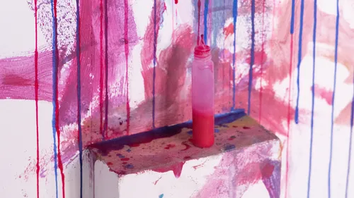 Farbflasche auf bunt bemalter Wand.