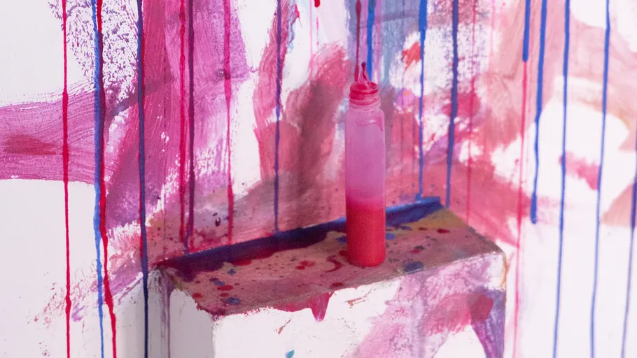 Paint bottle on colorful painted wall.