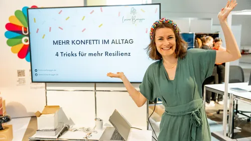 Woman smiling beside presentation screen at event.
