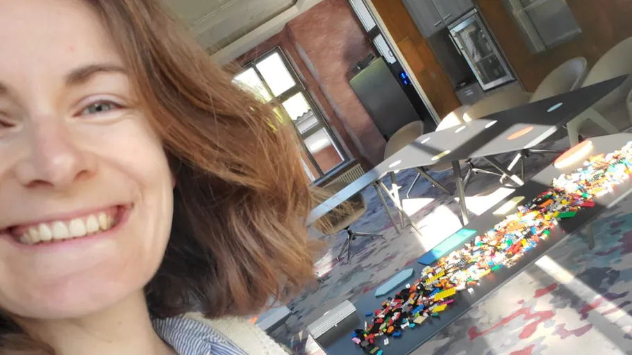 Smiling person, tables with scattered Lego bricks.