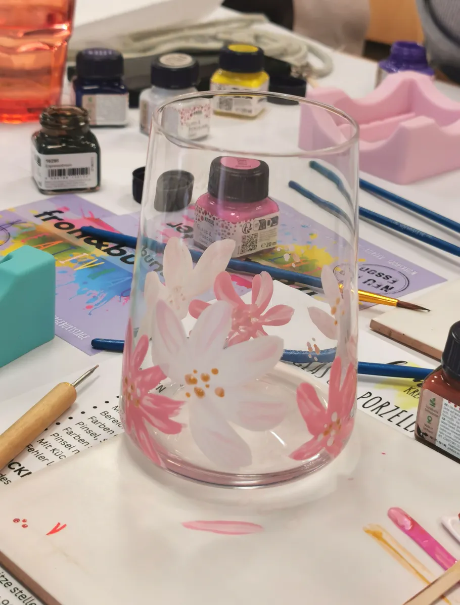Painted glass with floral design on table.