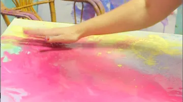 Hand verschmiert Farbe auf bunter Leinwand.