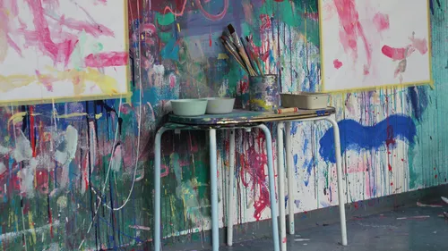 Art studio table with paintbrushes, colorful background.