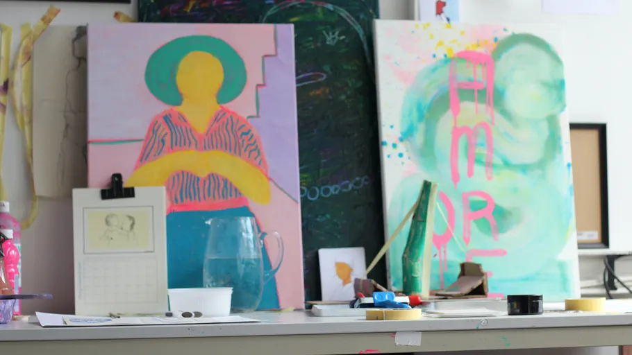 Abstract paintings on cluttered art studio desk.