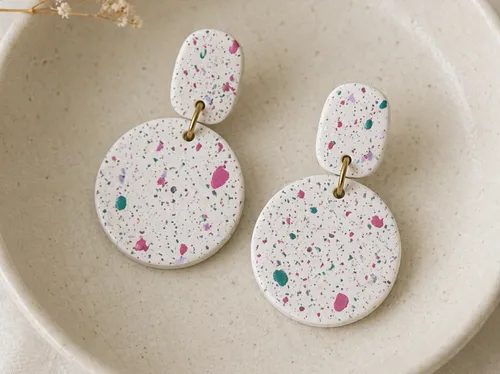 Speckled white earrings in a ceramic dish.