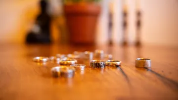 Silver rings scattered on wooden table.