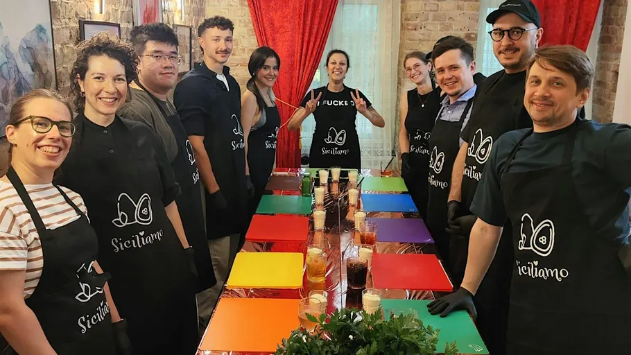 Group wearing aprons, standing around a table.