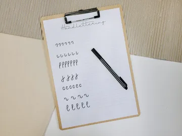 Handlettering-Seite mit kalligraphischen Übungen und Stift.