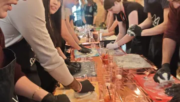 Menschen machen Pizzateig an einem Tisch.