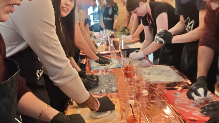 Menschen machen Pizzateig an einem Tisch.