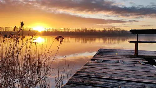 Sonnenuntergang über See mit Holzsteg.