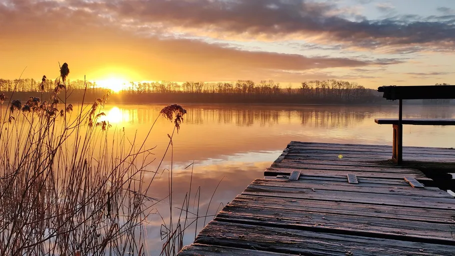 Sunset over lake with wooden pier.