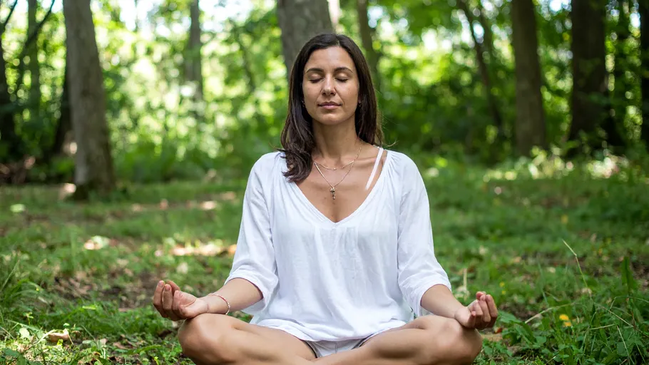 Woman meditating in a forest setting.