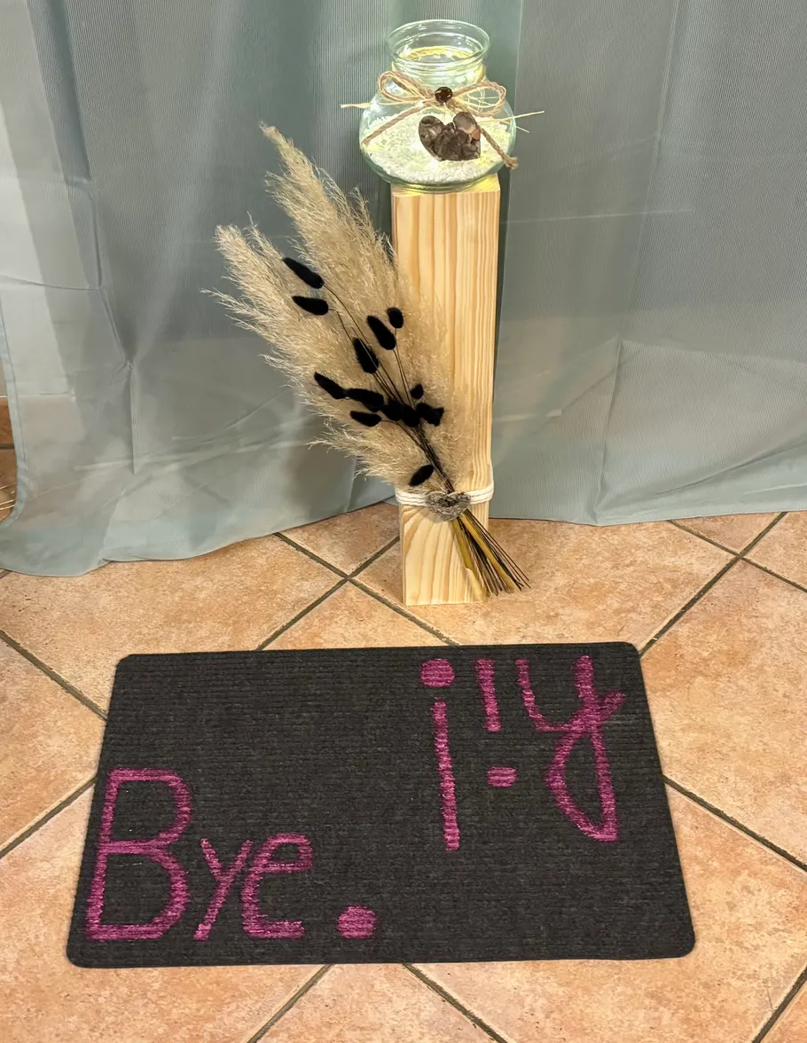 Doormat with decorative stand beside curtain.