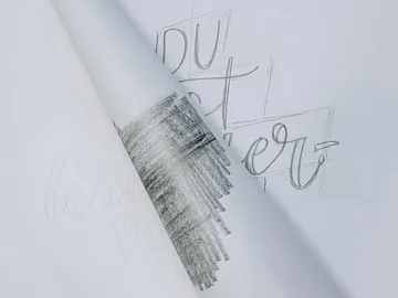 Paper with hand-drawn text and black pencil strokes.