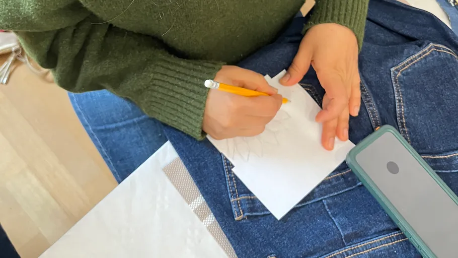Person drawing on paper with pencil indoors.