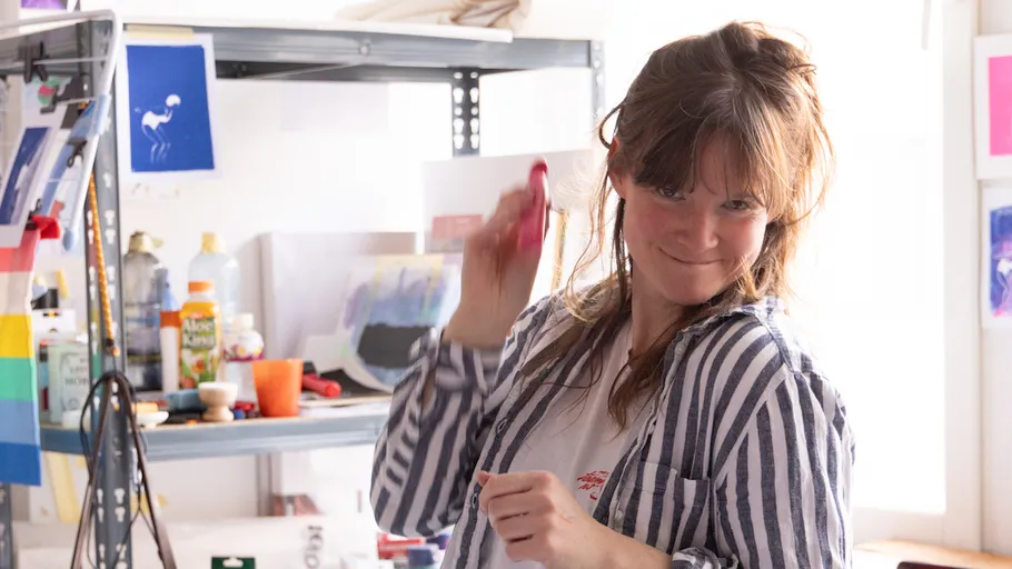Woman playfully shaking a spray can in studio.