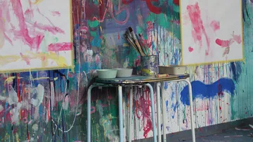 Kunststudio mit Farbspritzern und Malutensilien.