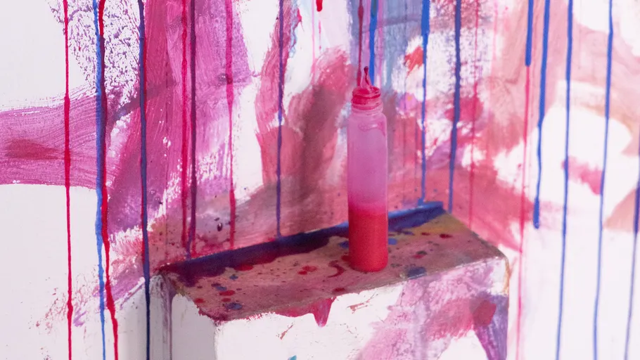 Pink paint bottle on splattered shelf.