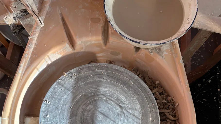 Pottery wheel with clay and slip bowl.