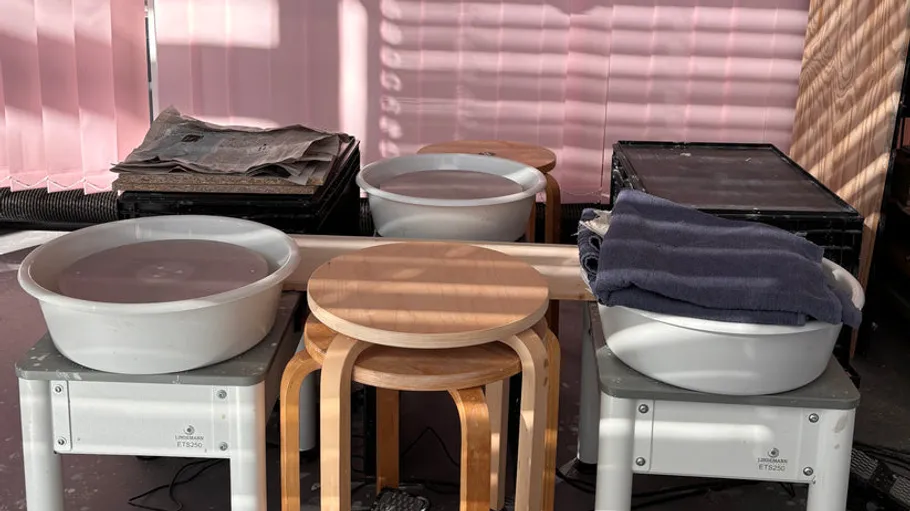 Plastikschüsseln, Hocker und Zeitungen auf Tisch.