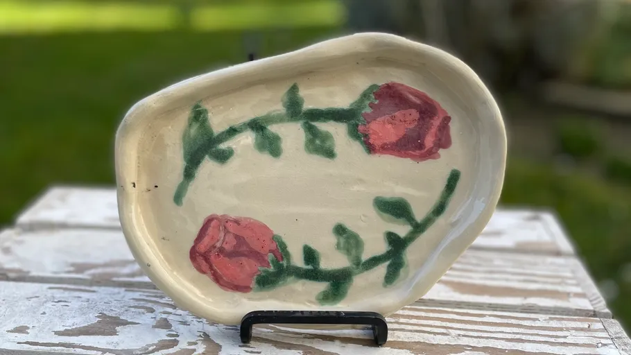 Handbemalter Keramikteller mit Rosendesign im Freien.