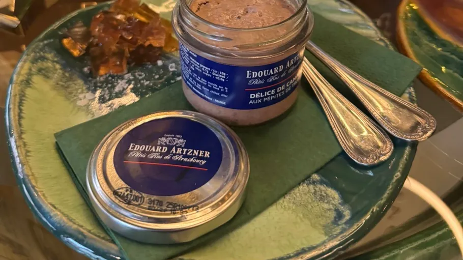 Jar of duck delight with cutlery on plate.