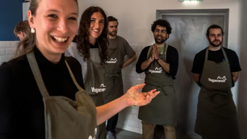 Gruppe von Menschen mit Schürzen in einer Küche.