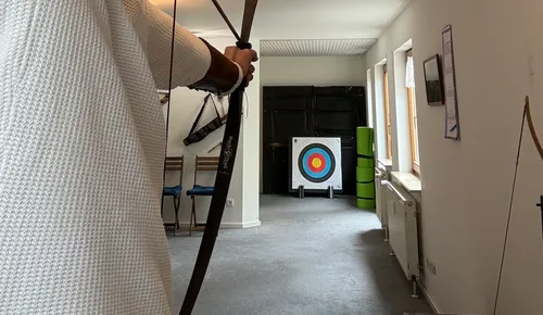 Archer aiming at target indoors.
