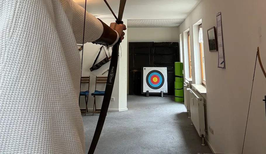 Archer aiming at target indoors.