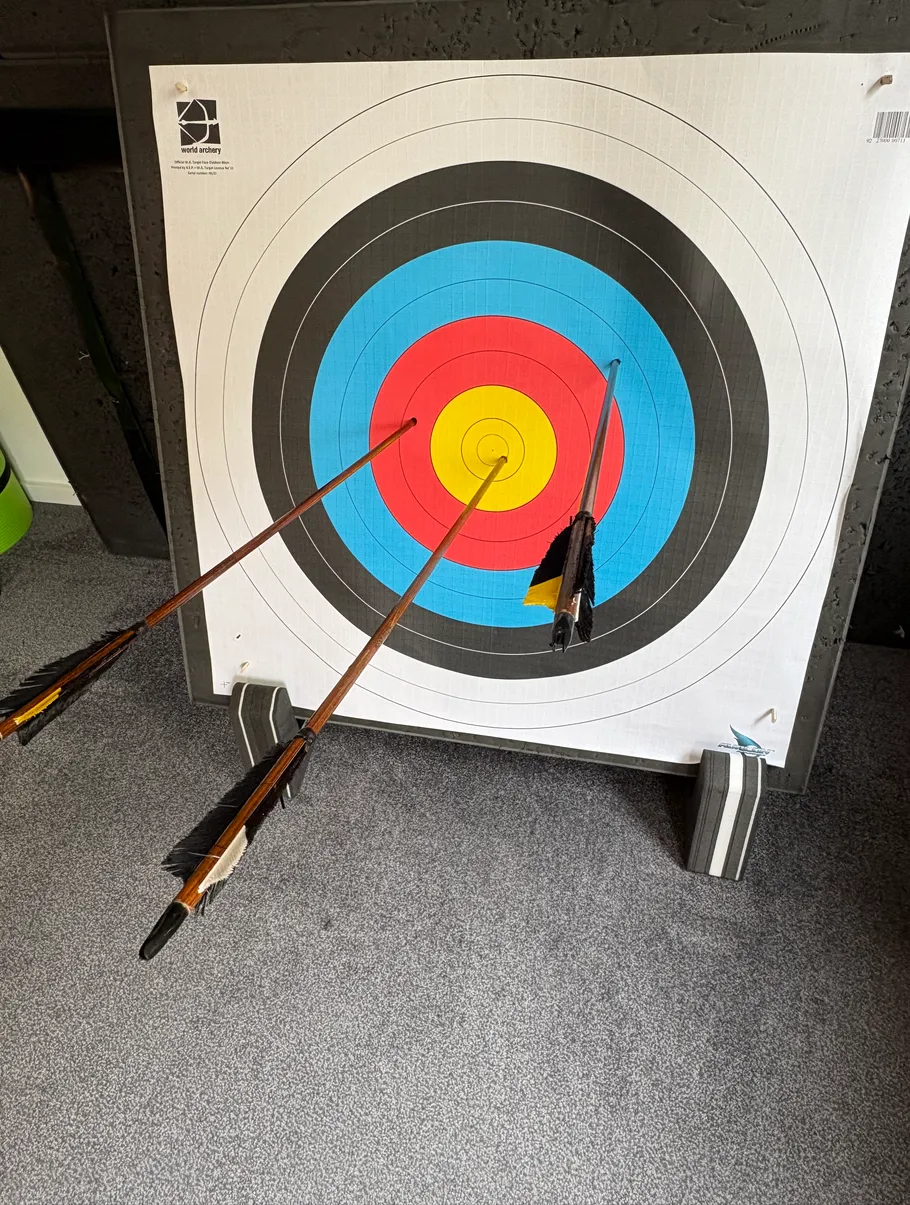 Archery target with three arrows in colored rings.