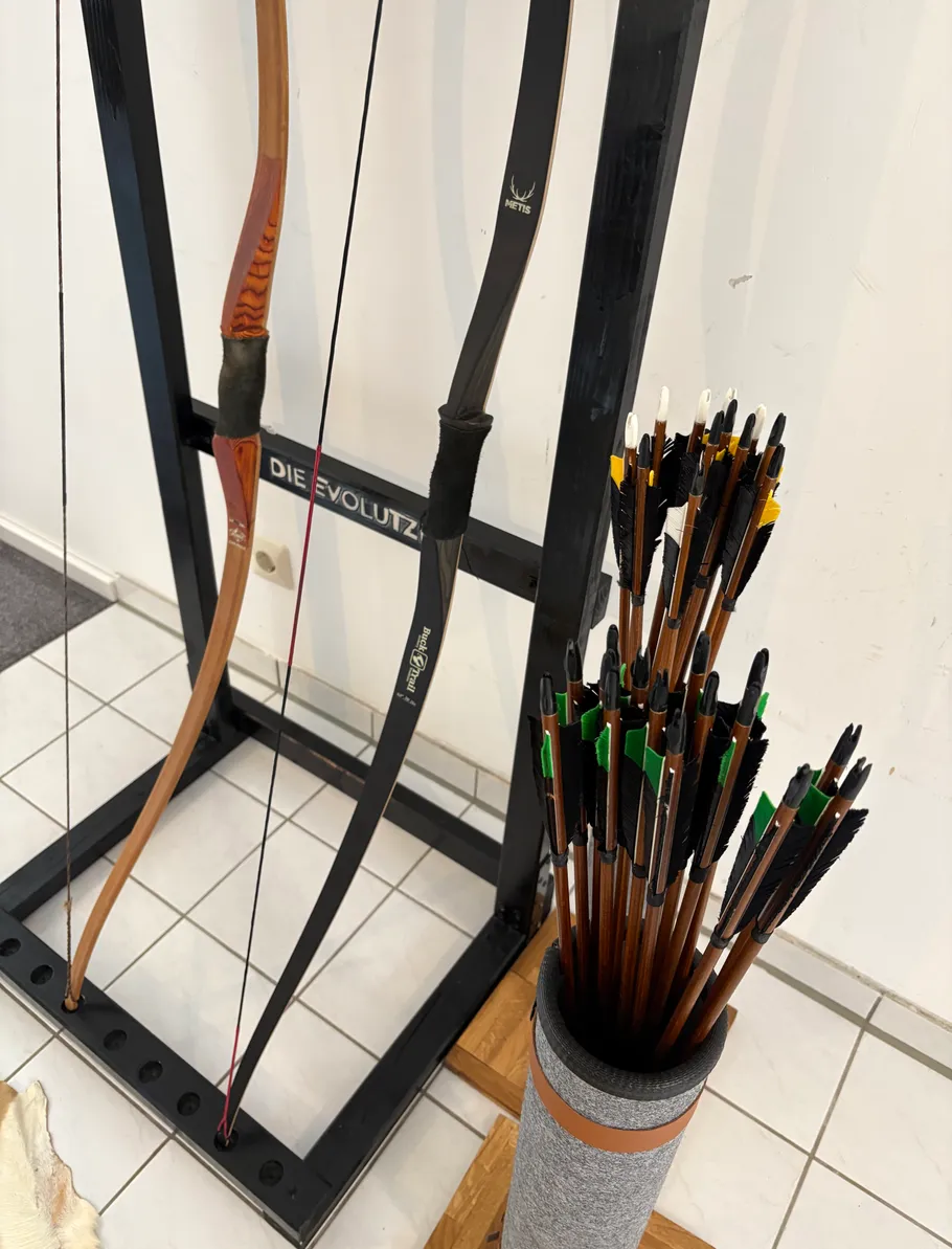 Bows hanging on rack, arrows in quiver.