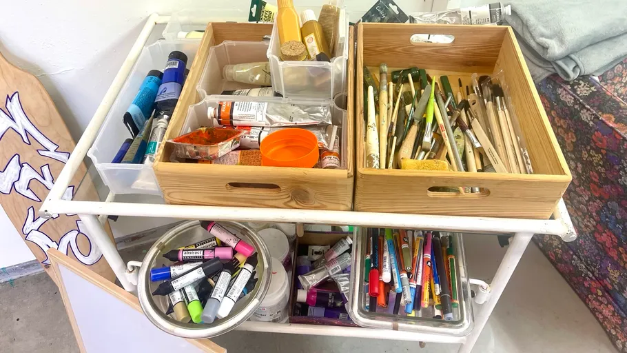 Art supplies organized in wooden and plastic trays.