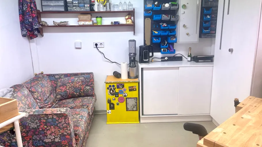 Gemütliche Werkstatt mit Werkzeugen, Sofa und gelbem Kühlschrank.