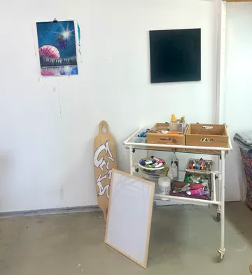 Colorful artwork and blank canvas on white wall.