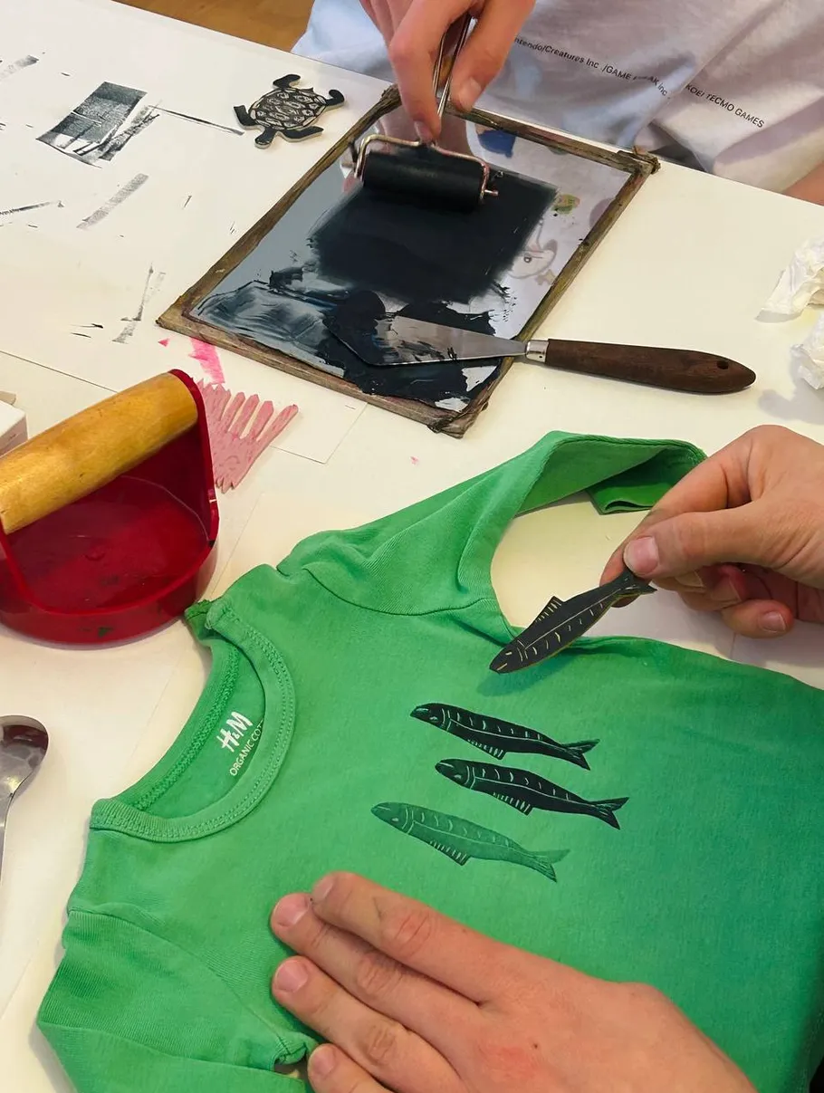 Green shirt being printed with black fish design.