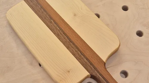 Holzschneidebrett auf gelochter Oberfläche.