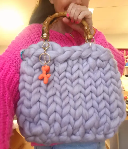 Frau hält grob gestrickte Handtasche drinnen.